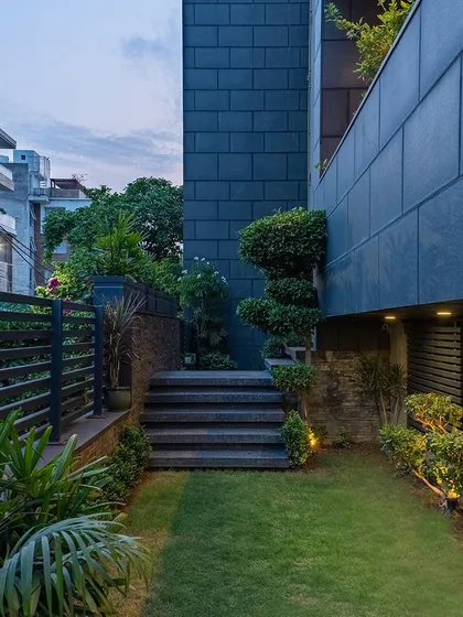 Biophilic design, or connecting architecture with nature, is one of my core principles. This home's exterior and entryway feature lush greenery, natural stone steps, and modern slate-colored tiling, creating a transformative and welcoming outdoor living space.