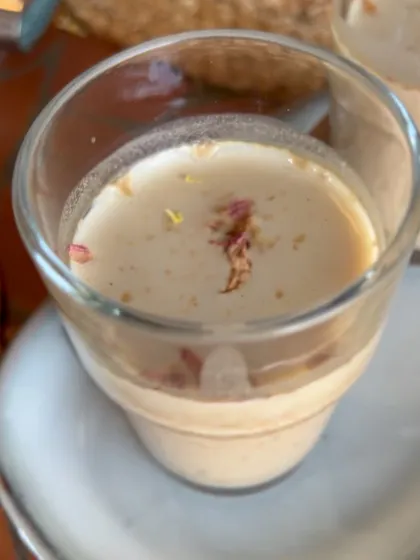 A creamy, dairy-free dessert served in a glass, garnished with delicate rose petals. This could be a plant-based kheer or panna cotta, demonstrating the elegance of healthy sweets.