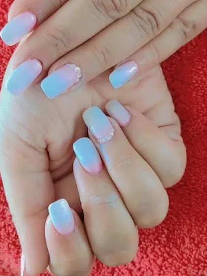 A soft and dreamy ombre effect using pastel blue and pink. The colors blend seamlessly, creating a cotton candy or sunset-inspired look on these square-shaped nails.