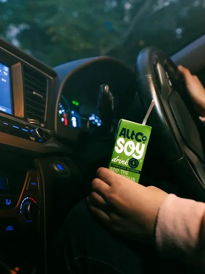 A shot of Alt Co. soy milk in a car at night. This image suggests the product is a convenient option for people on the move, perfect for a late-night drive or commute.