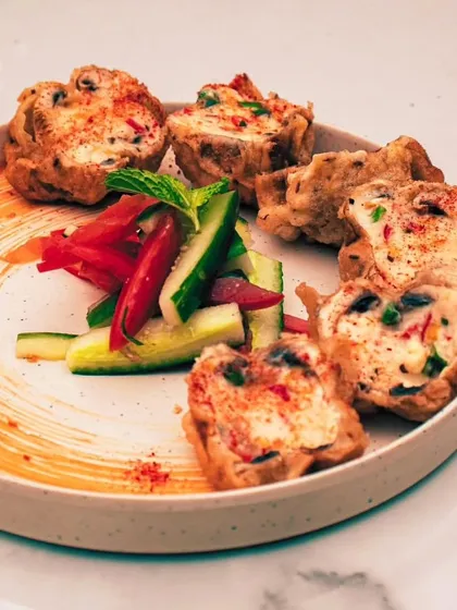 A deconstructed appetizer, beautifully plated with a swirl of sauce and fresh salad, highlighting our modern culinary style.