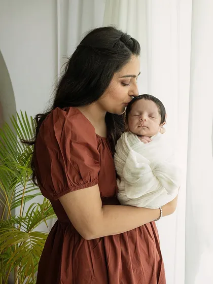 A mother's quiet moment with her newborn. The soft window light creates a serene and angelic mood, perfect for a timeless mother and child portrait.