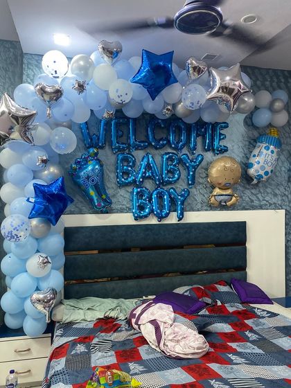 A 'Welcome Baby Boy' decoration for a bedroom. The setup includes a balloon arch over the headboard and various star and baby-themed foil balloons.