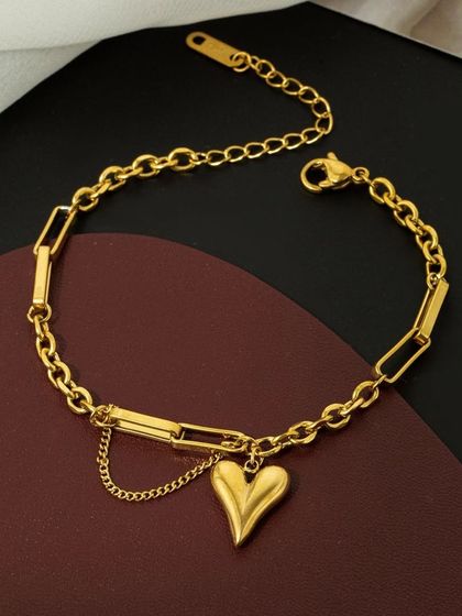 A close-up of the mixed-chain heart pendant bracelet. The combination of paperclip links, a classic chain, and a delicate dangle chain creates a unique, layered look.