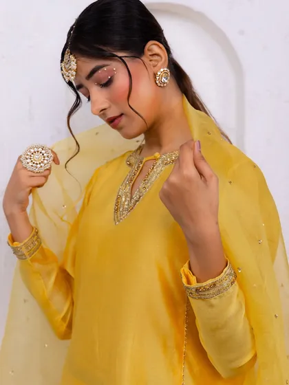 A close-up on the details of the yellow suit, from the intricate neckline embroidery to the statement ring and maang tikka.