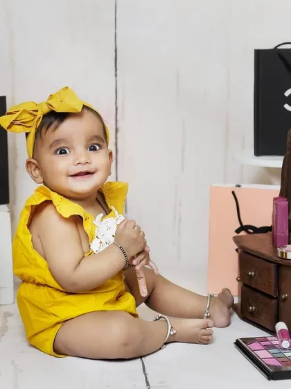 A makeup and shopping themed sitter session for a little glamour girl. The setup includes a mini vanity, makeup props, and designer shopping bags.
