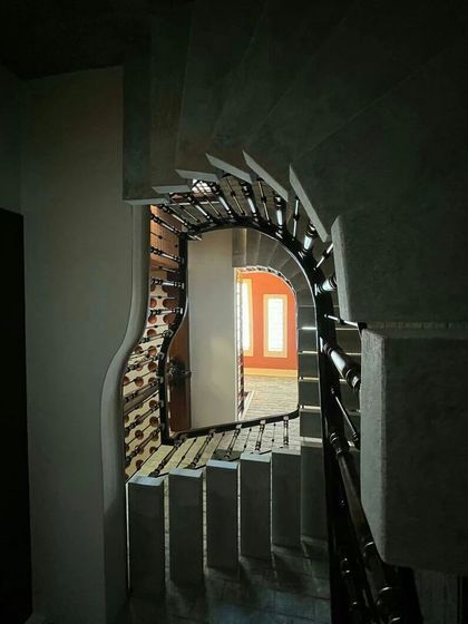 A dramatic, artistic shot looking down the spiral of a staircase, framing a distant room.