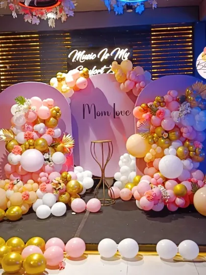 A sophisticated and artistic setup for a special occasion, featuring dual arched backdrops and organic balloon garlands in shades of pink, peach, and gold. This decor is perfect for birthdays, anniversaries, or bridal showers.