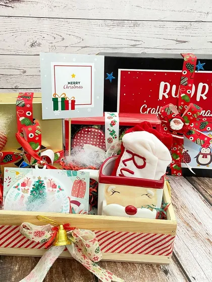 A personalized 'Crafty Christmas Box' for kids, filled with art supplies and a snowman toy, all arranged in a festive wooden crate.