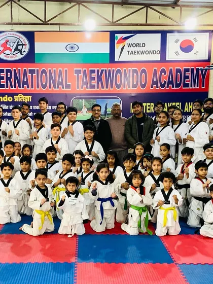 Our students posing together after a successful belt test. The mix of different colored belts, from yellow and green to blue and black, shows a clear path of progression for everyone who joins.