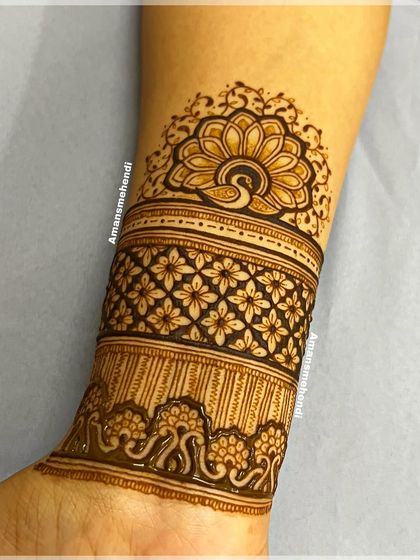 A detailed close-up of a beautiful arm band. The design features a band of intricate flowers, topped with a peacock mandala.
