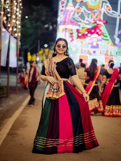 A full-length portrait from a Garba night. Her multi-colored lehenga and cool sunglasses create a fun, festive, and modern-traditional look.