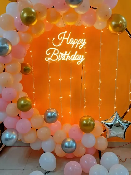 A peach, pink, and gold balloon ring with fairy lights, perfect for an intimate home birthday celebration.