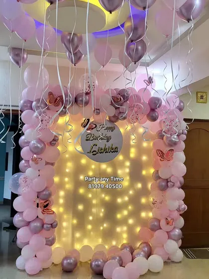 A simple yet beautiful butterfly theme decoration for a home party. This setup features a balloon arch against a curtain of fairy lights, with butterfly stickers for detail.