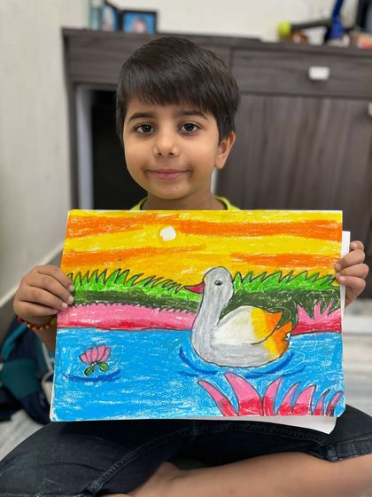 A first-grade student shows off his beautiful drawing of a duck swimming in a pond at sunset. In my drawing classes for kids, we focus on basic shapes and colour blending to create charming animal art.