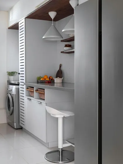 In this compact kitchen, we designed a breakfast counter with a stainless steel top to serve as a quick dining spot. The design incorporates storage and a utility area within a tight footprint.