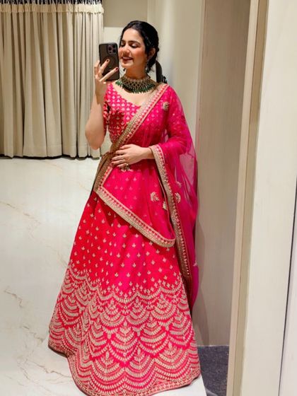 A mirror selfie in a stunning pink bridal lehenga, showing off the intricate gold embroidery. This is a classic look for a bride.