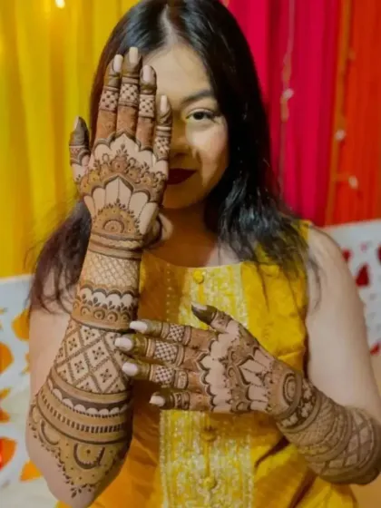 A happy client posing with her beautiful bridal mehndi at her home ceremony.