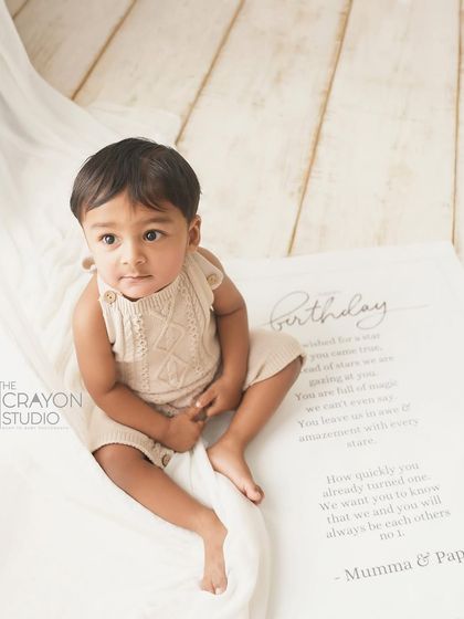 A quiet, contemplative moment from the birthday boy, sitting on a personalized birthday banner from his parents.