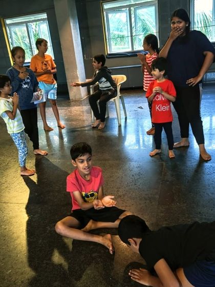 A group of children engaged in a theatre game. These games are not just for fun; they are designed to build essential skills like listening, concentration, and teamwork.