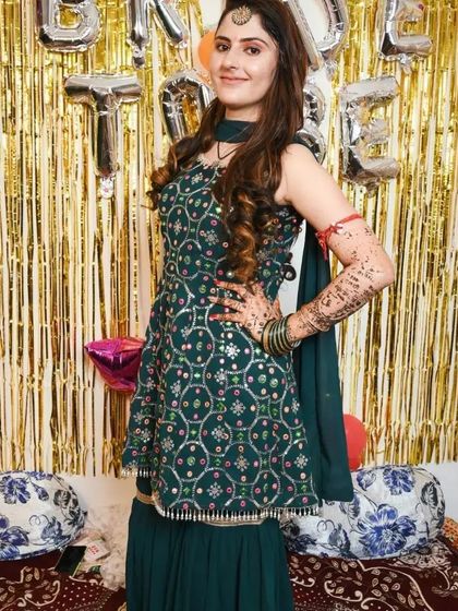 A bride-to-be wearing a green sharara suit with silver work for one of her pre-wedding functions.