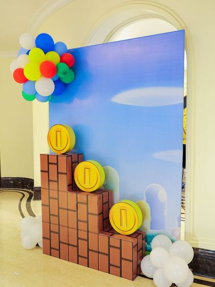 A Super Mario themed photo spot with brick blocks and gold coins set against a classic blue sky backdrop. The setup is perfect for guests to take memorable pictures.