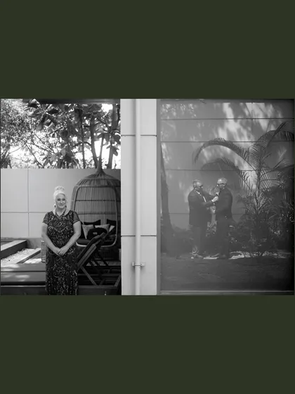 A mother watches on, her reflection captured alongside her son's happiness. This black and white shot speaks volumes about family love that travels across the globe to witness a new beginning.