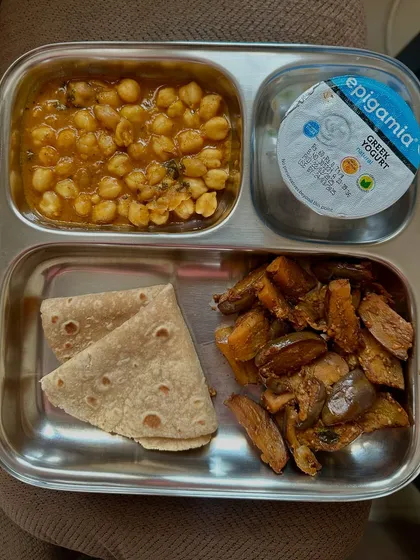 This plate features chapati, channa masala, and sautéed sweet potato with Greek yogurt. It's a satisfying and balanced vegetarian meal.