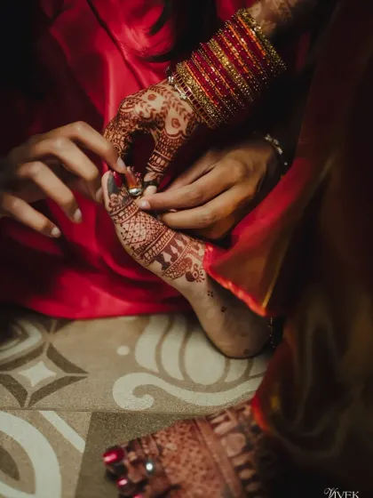 A close-up of a wedding ritual, focusing on the bride's foot with its rich henna stain.