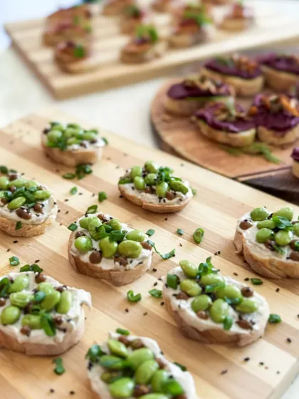 A close-up of our edamame tartines, topped with sesame seeds and fresh herbs. A perfect bite-sized snack for any occasion.