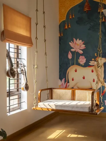 In the living room of our Banashankari residence, a traditional wooden swing becomes a playful centerpiece. This space embodies my approach of integrating nostalgic elements into a modern, light-filled home, using Jaisalmer stone flooring and a wood-and-cane false ceiling to create an earthy, grounded feel.