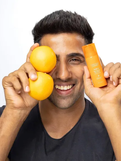 Another playful and energetic model shot. The use of fresh oranges as props reinforces the Vitamin C theme, and the model's genuine smile makes the product feel approachable and fun.