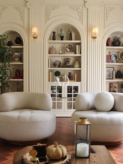 This lounge area is defined by its architectural backdrop of fluted columns and arched, built-in shelving. The soft, sculptural armchairs provide a contemporary contrast, creating a space that is both classically Parisian and comfortably modern.