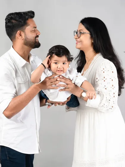 The happiness of holding your baby. This candid moment shows the parents' delight as they interact with their little one, who is looking right at the camera.