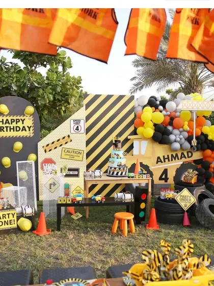 The main backdrop for the construction party, featuring a personalized name, a crane, and a dessert table filled with themed treats.