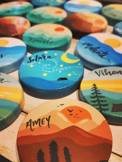 A collection of personalized magnets, each with a unique name and a different travel-inspired design, from mountains to starry skies.