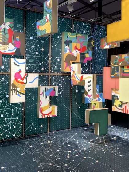 A wide view of the 'Solo Commerce' installation, where illustrated blocks float within a space defined by network-like graphics. The design explores the freedom of choice, location, and lifestyle that characterizes the modern gig economy.