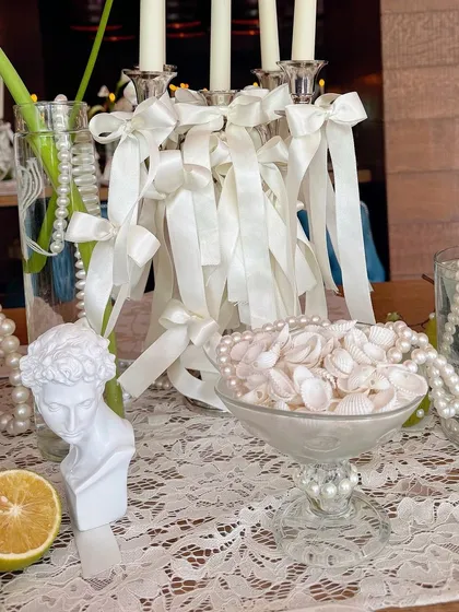 A close-up of the table details, including a small bust statue, seashells, and lace, creating a classic and romantic vibe.