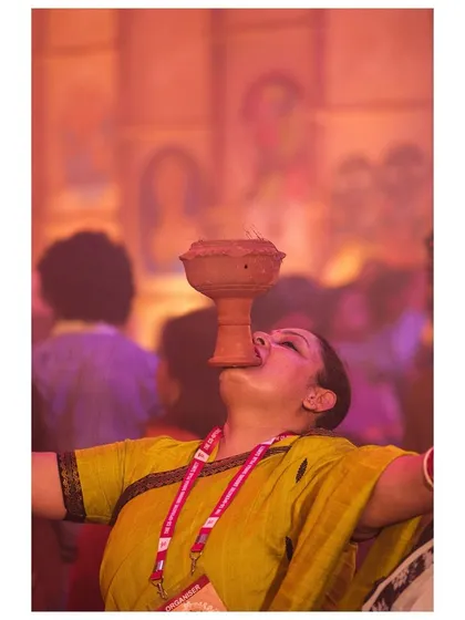 Lost in devotion, a woman balances the smoking dhunuchi in her mouth, a feat of faith and balance during the Durga Puja celebrations.