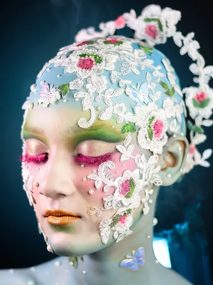 A close-up of the eye makeup, featuring pink lashes and soft, blended colors.