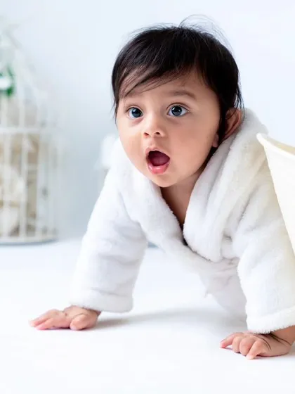 A curious peek from behind the tub. The clean, all-white set with minimal props keeps the focus on your baby's expressions during the bath session.