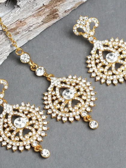 A delicate gold-plated earring and maang tika set with white stones.