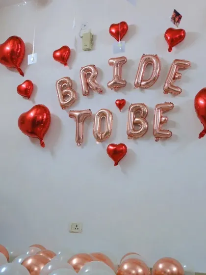 A close-up of the 'BRIDE TO BE' foil balloon banner, surrounded by red heart-shaped balloons for a romantic and celebratory feel.