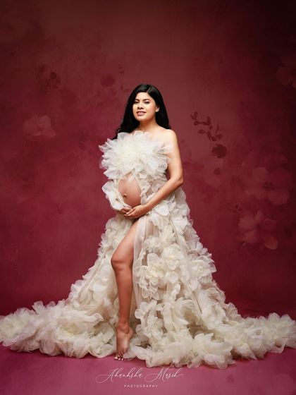 A full-length view of the stunning white floral gown against a deep pink backdrop, showcasing its incredible texture and form.