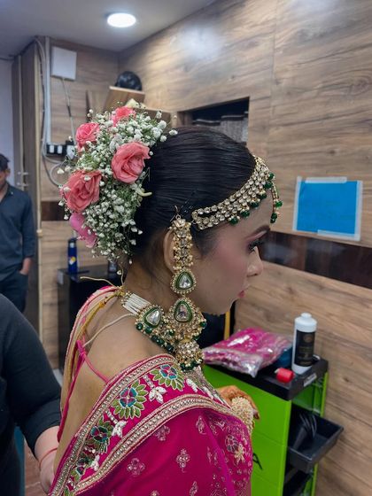 A side profile showcasing the intricate floral hair bun we created for our bride. We use a mix of fresh flowers like roses and baby's breath to add a touch of natural beauty to the traditional bridal hairstyle.