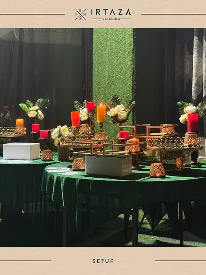 A pre-event shot of a dessert and appetizer station setup with green table linens. The arrangement of golden platters and candle holders shows the careful planning that goes into every display before guests arrive.