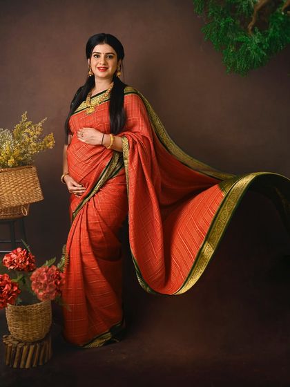 The flowing pallu of the saree adds a beautiful sense of movement and drama to this standing portrait, creating a dynamic and elegant shot.