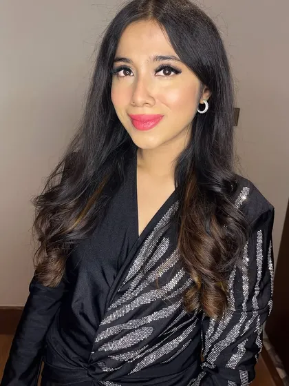 A close-up portrait. The makeup features a sharp wing, shimmery eyeshadow, and a bright pink lip.