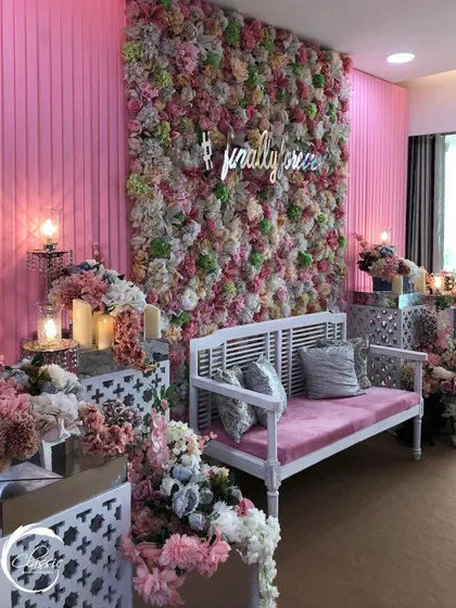 A wider view of the pink-themed Mehendi, showing how the flower wall, seating, and side floral arrangements all work together to create a fully immersive, romantic environment.