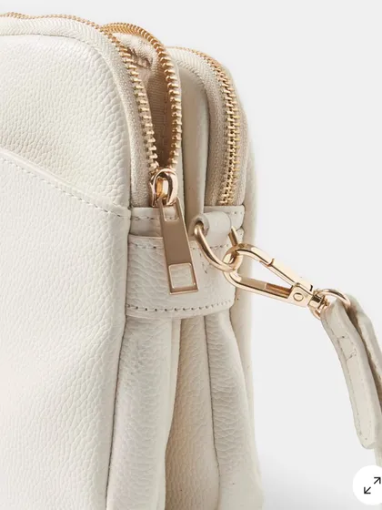 A close up detail of the zipper and clasp on the Australia Crossbody bag. The hardware is sturdy and has a beautiful polished gold finish.
